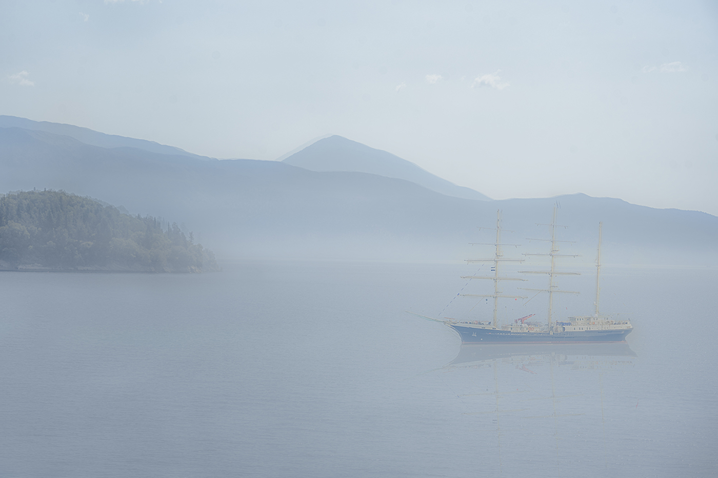 Daw seascape with sailing boat and mountains